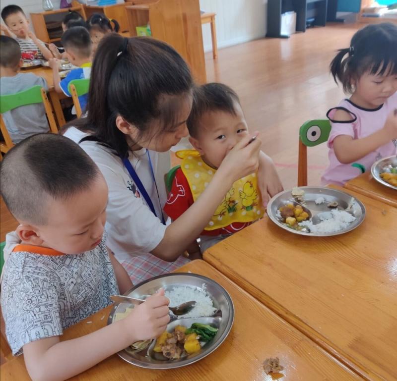 实训学生在喂小班的小朋友吃饭.jpg